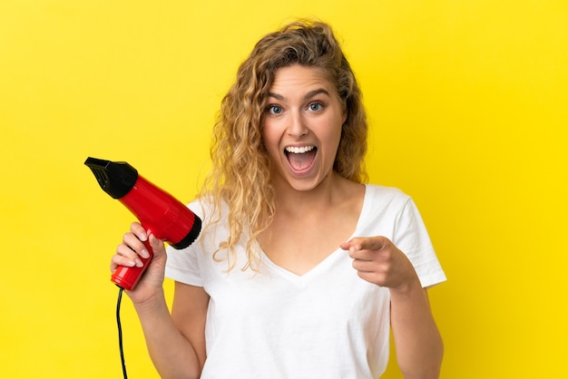 Young blonde woman holding a hairdryer
