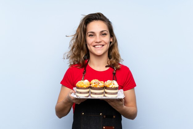 Young blonde woman holding mini cakes