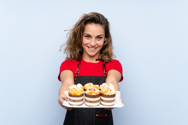 Young blonde woman holding mini cakes