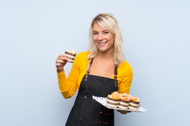 Young blonde woman holding mini cakes