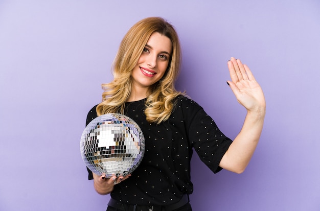 Young blonde woman holding a night party ball isolated smiling cheerful showing number five with fingers.