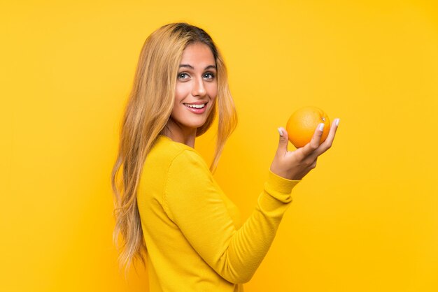 Young blonde woman holding an orange