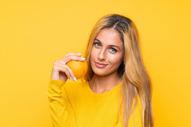 Young blonde woman holding an orange