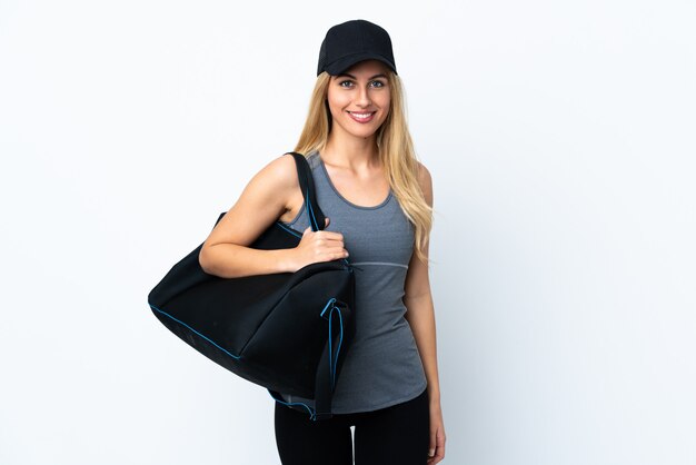 Young blonde woman holding a sport bag over isolated white wall