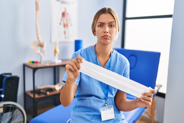 Foto giovane donna bionda che tiene la terapia strip band scettica e nervosa, accigliata sconvolta a causa del problema. persona negativa.