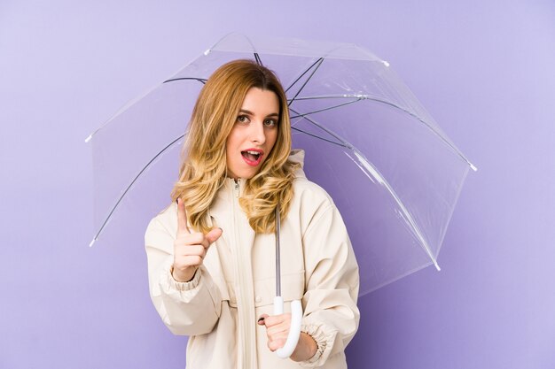 Young blonde woman holding an umbrella isolated Young blonde woman holding an umbrella isolated having an idea, inspiration concept.