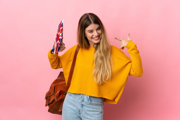 Young blonde woman holding an United Kingdom flag isolated on white space giving a thumbs up gesture