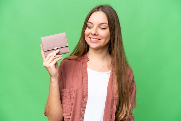 Young blonde woman holding a wallet over isolated chroma key background with happy expression