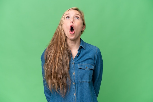 Young blonde woman over isolated background looking up and with surprised expression