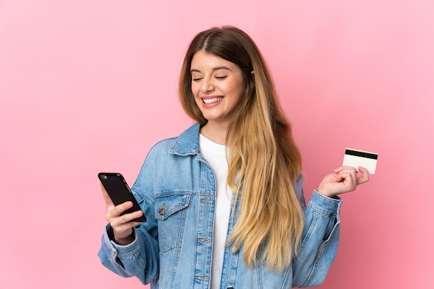 Young blonde woman isolated buying with the mobile with a credit card