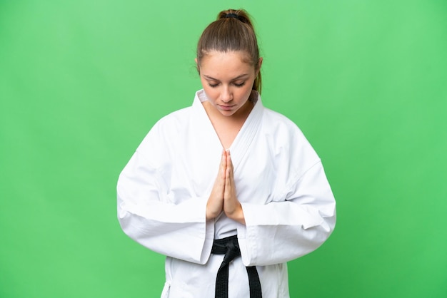 Young blonde woman over isolated chroma key background doing karate and saluting