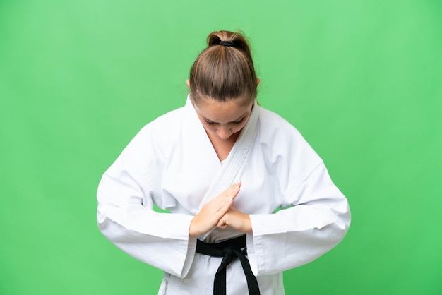 Giovane donna bionda su sfondo chroma key isolato facendo karate e salutando