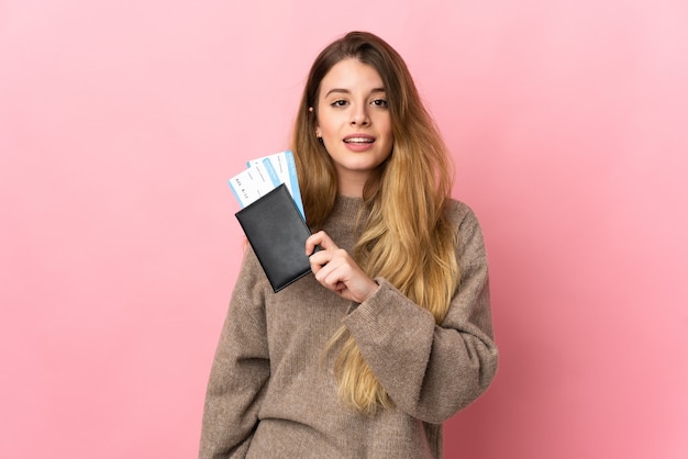 Young blonde woman over isolated happy in vacation with passport and plane tickets