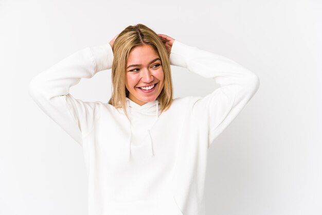 Young blonde woman isolated laughs joyfully keeping hands on head