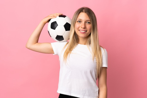 Giovane donna bionda isolata sulla parete rosa con pallone da calcio