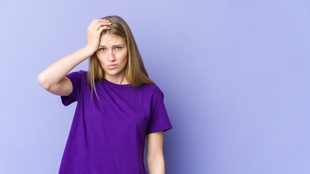 Young blonde woman isolated on purple wall being shocked, she has remembered important meeting.