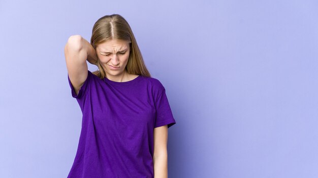 Young blonde woman isolated on purple wall suffering neck pain due to sedentary lifestyle.