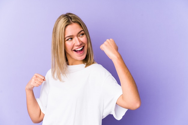 Young blonde woman isolated raising fist after a victory