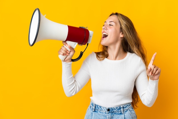 Young blonde woman isolated shouting through a megaphone to announce something