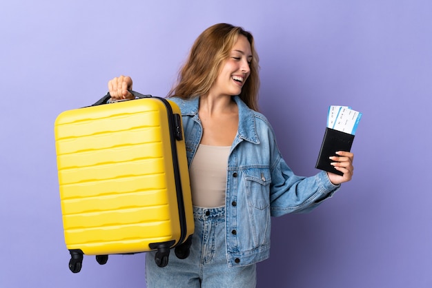 Young blonde woman isolated in vacation with suitcase passport