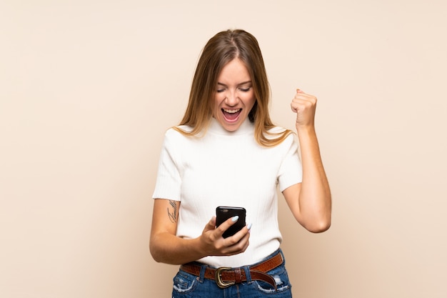 Foto giovane donna bionda sopra la parete isolata facendo uso del telefono cellulare