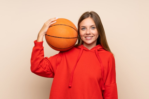 Young blonde woman over isolated wall with ball of basketball