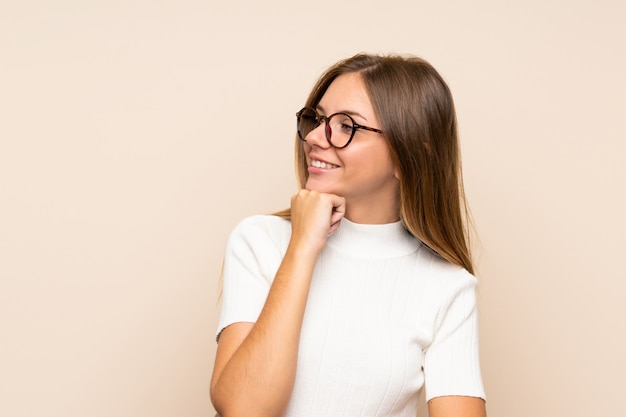 Young blonde woman over isolated wall with glasses