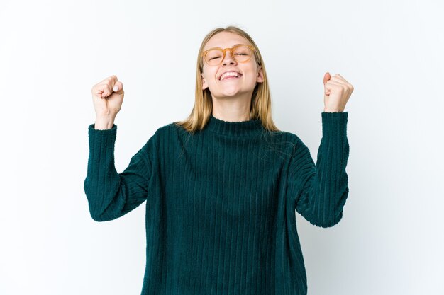 Young blonde woman isolated on white background celebrating a victory, passion and enthusiasm, happy expression.