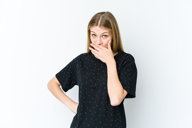 Young blonde woman isolated on white background covering mouth with hands looking worried.