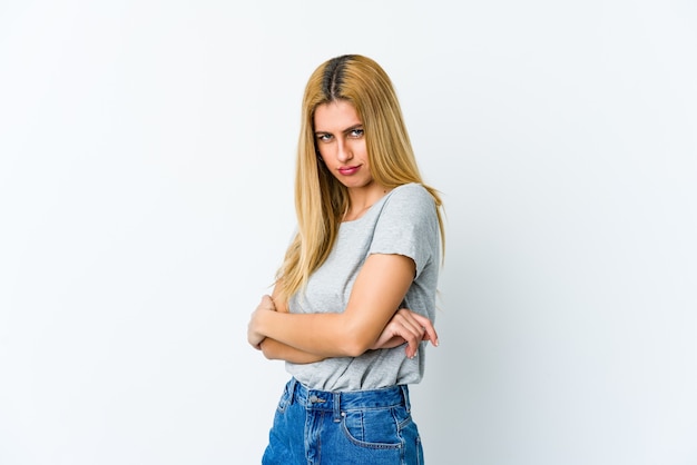 Young blonde woman isolated on white background frowning face in displeasure, keeps arms folded.