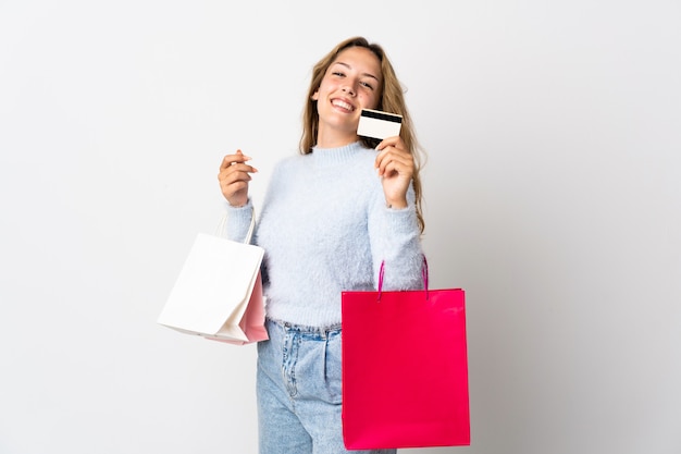 Foto giovane donna bionda isolata su sfondo bianco tenendo le borse della spesa e una carta di credito