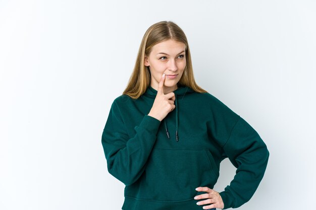 Young blonde woman isolated on white background looking sideways with doubtful and skeptical expression.