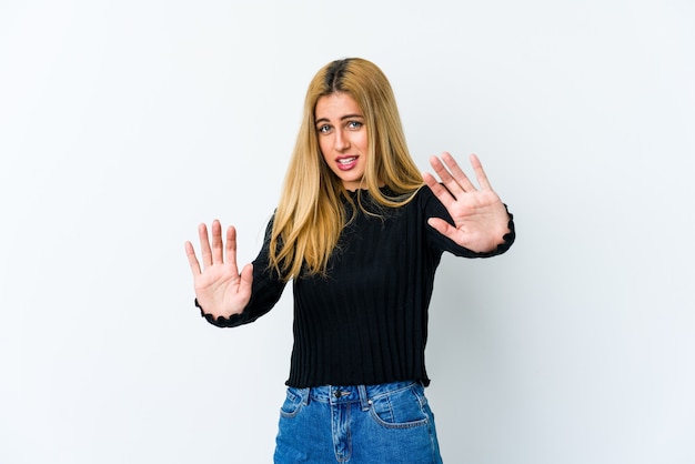 Young blonde woman isolated on white rejecting someone showing a gesture of disgust.