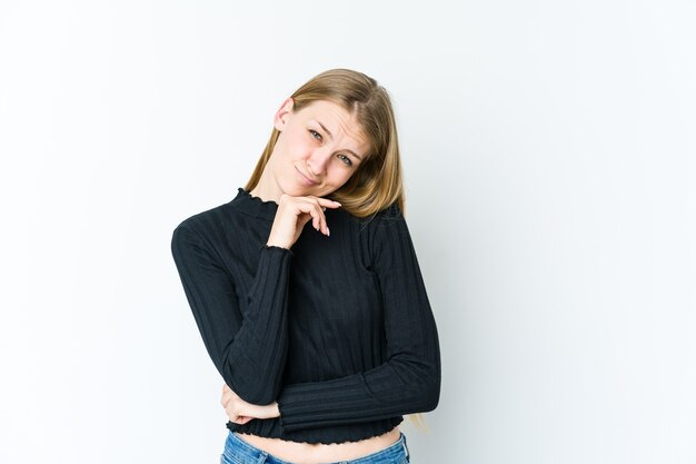 Young blonde woman isolated on white wall tired of a repetitive task.