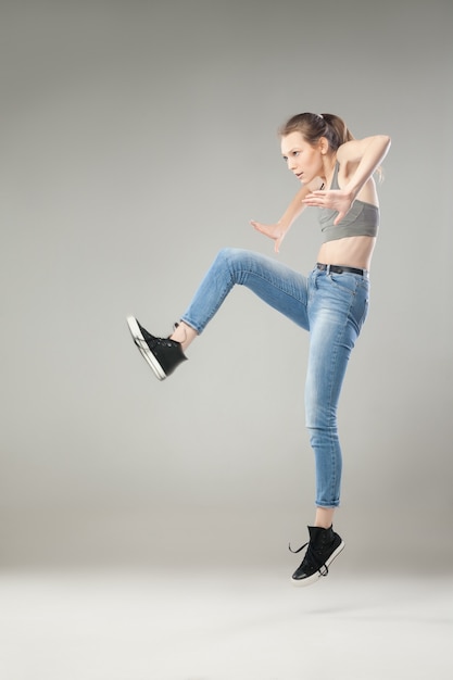 Young blonde woman jumping in mid air while looking away.Studio shot