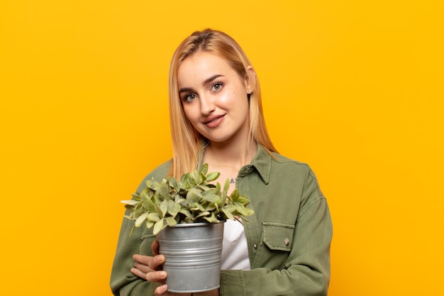 Young blonde woman laughing happily with arms crossed, with a relaxed, positive and satisfied pose