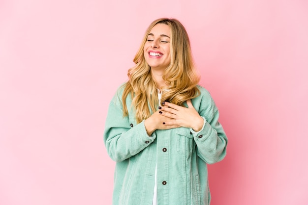 Young blonde woman laughing keeping hands on heart