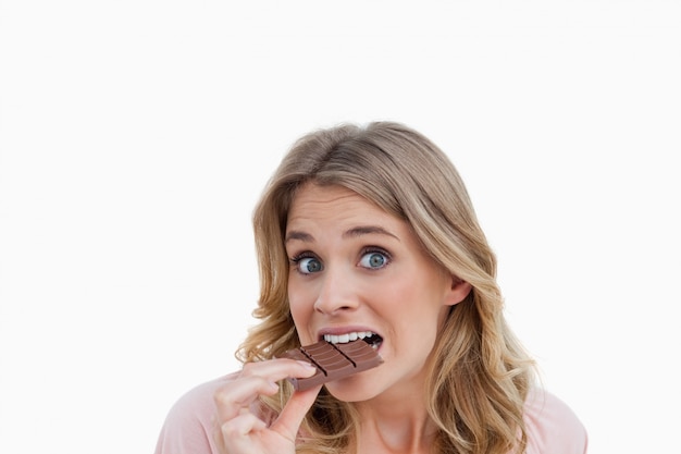 Photo young blonde woman looking at the camera while eating chocolate