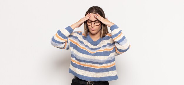 Young blonde woman looking concentrated, thoughtful and inspired, brainstorming and imagining with hands on forehead