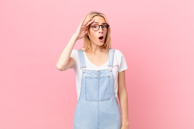 Young blonde woman looking happy, astonished and surprised