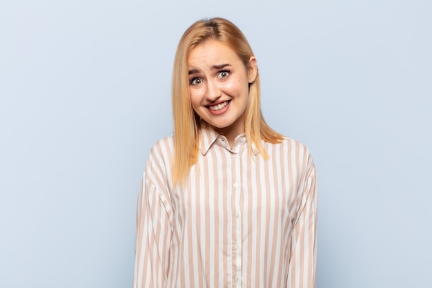 Young blonde woman looking happy and goofy with a broad, fun, loony smile and eyes wide open