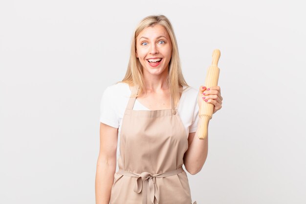 Young blonde woman looking happy and pleasantly surprised. baker concept