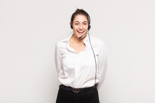 Young blonde woman looking happy and pleasantly surprised, excited with a fascinated and shocked expression