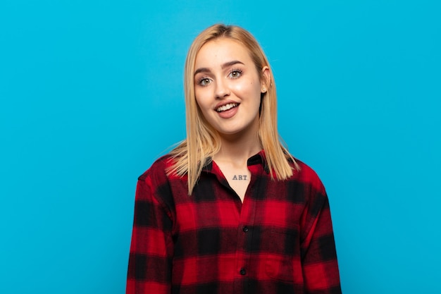 Young blonde woman looking happy and pleasantly surprised, excited with a fascinated and shocked expression