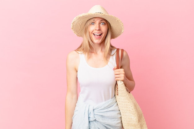 Young blonde woman looking happy and pleasantly surprised