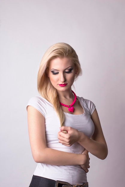 Young blonde woman looking on her hair. Studio shot