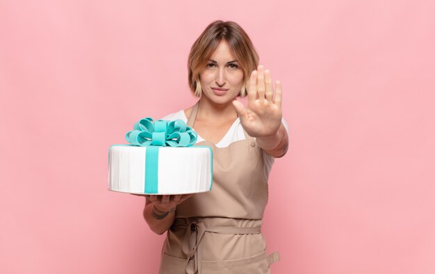 Young blonde woman looking serious, stern, displeased and angry showing open palm making stop gesture