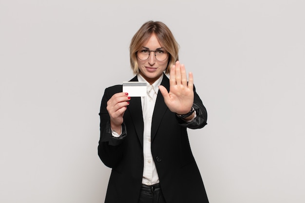 Young blonde woman looking serious, stern, displeased and angry showing open palm making stop gesture