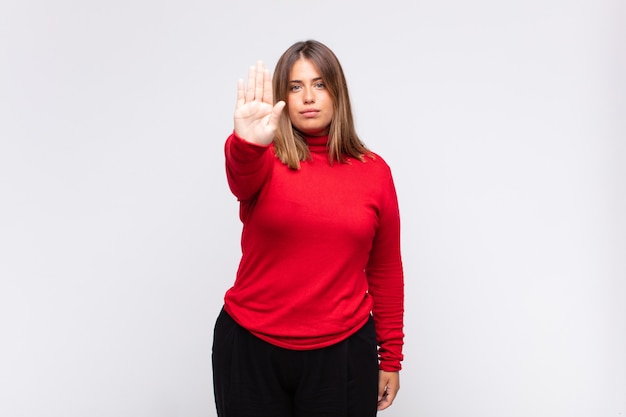 Young blonde woman looking serious, stern, displeased and angry showing open palm making stop gesture