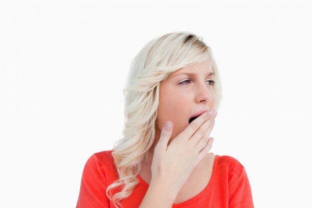 Young blonde woman looking on the side while yawning